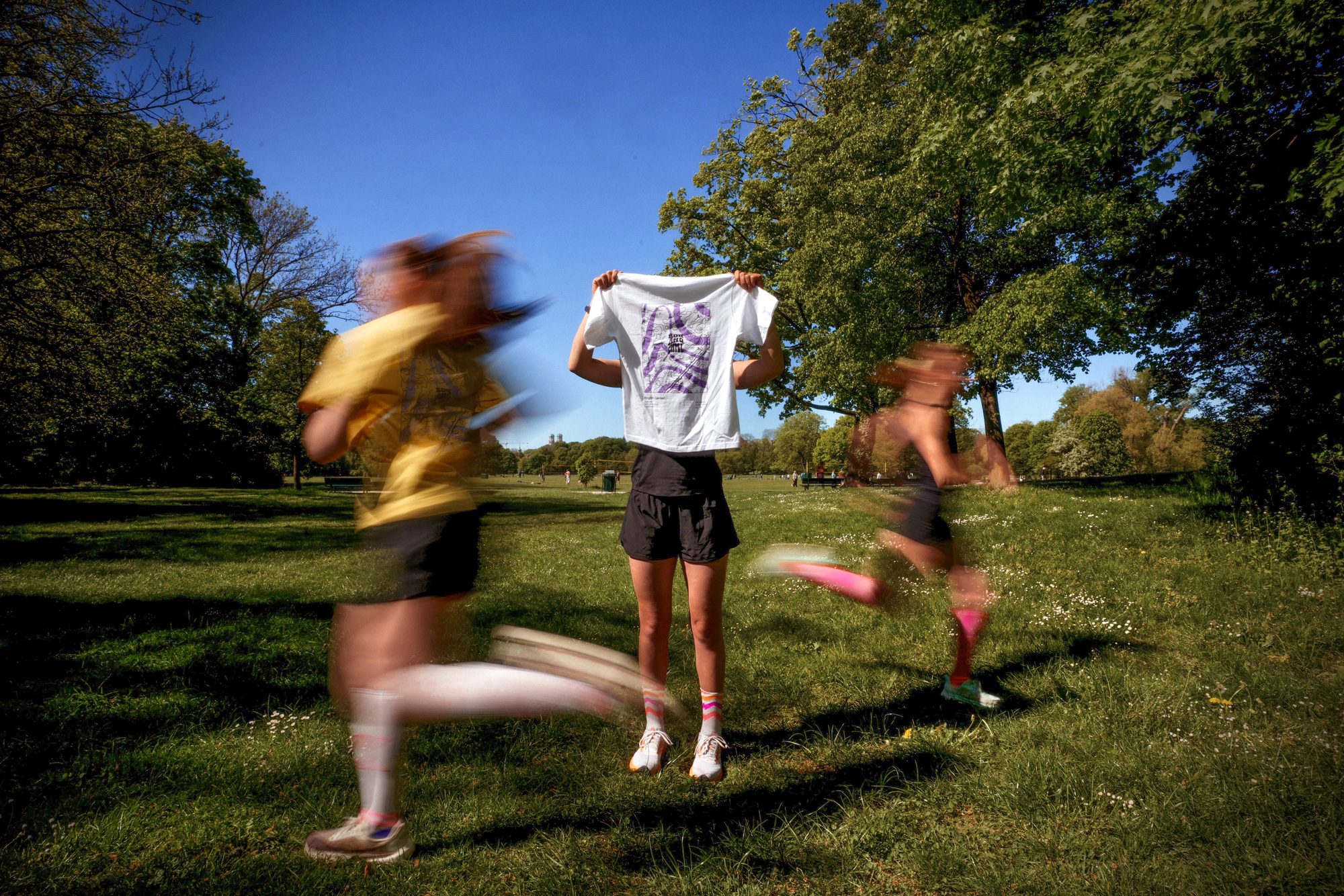Run and Chill members at a Munich training session holding a yellow Run and Chill tee with the English Garden topo print