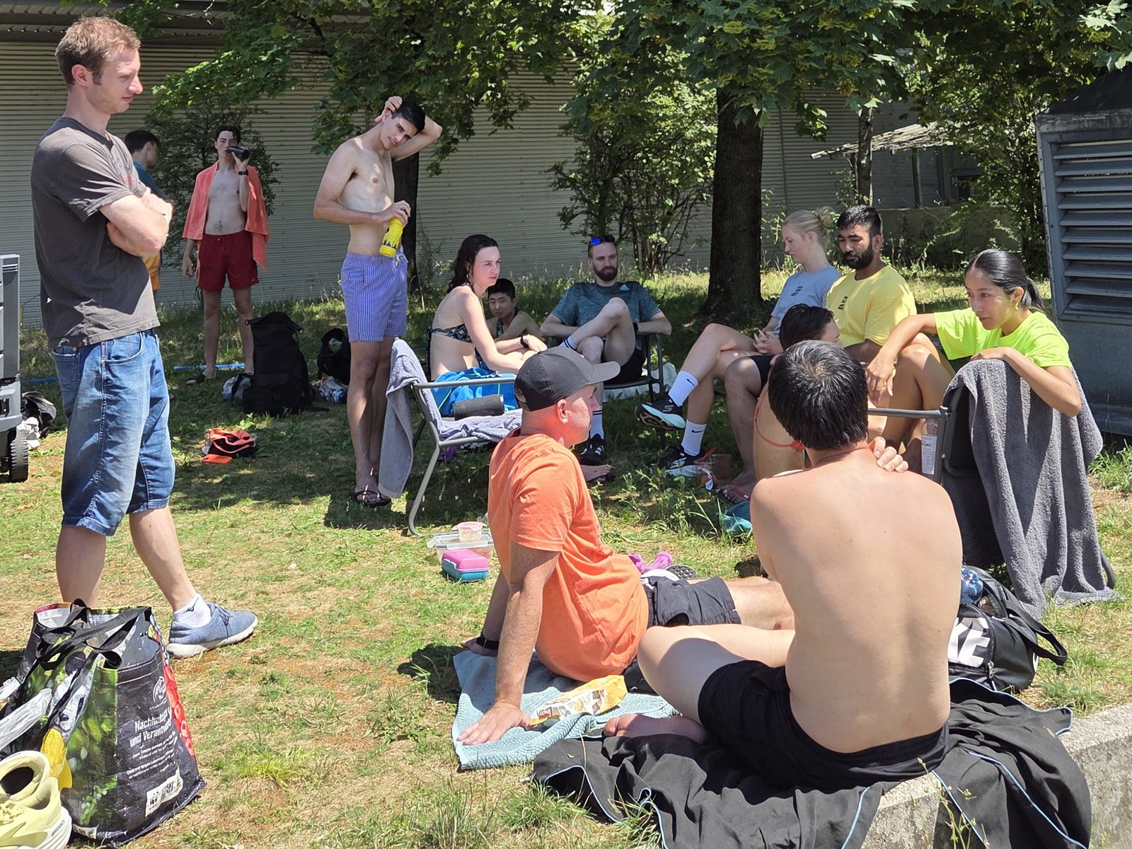Run and Chill members sitting on the grass outside the sauna with towels and drinks, in the shade of a big tree.